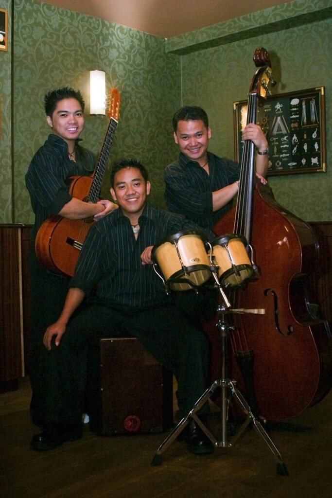 3 man playing music in corner of pub